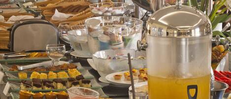 A buffet setup with various food items, a juice dispenser, and coffee makers.
