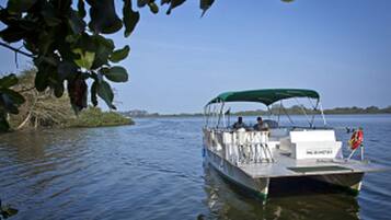 A boat with a green canopy, passengers, and a lifebuoy on the deck.
