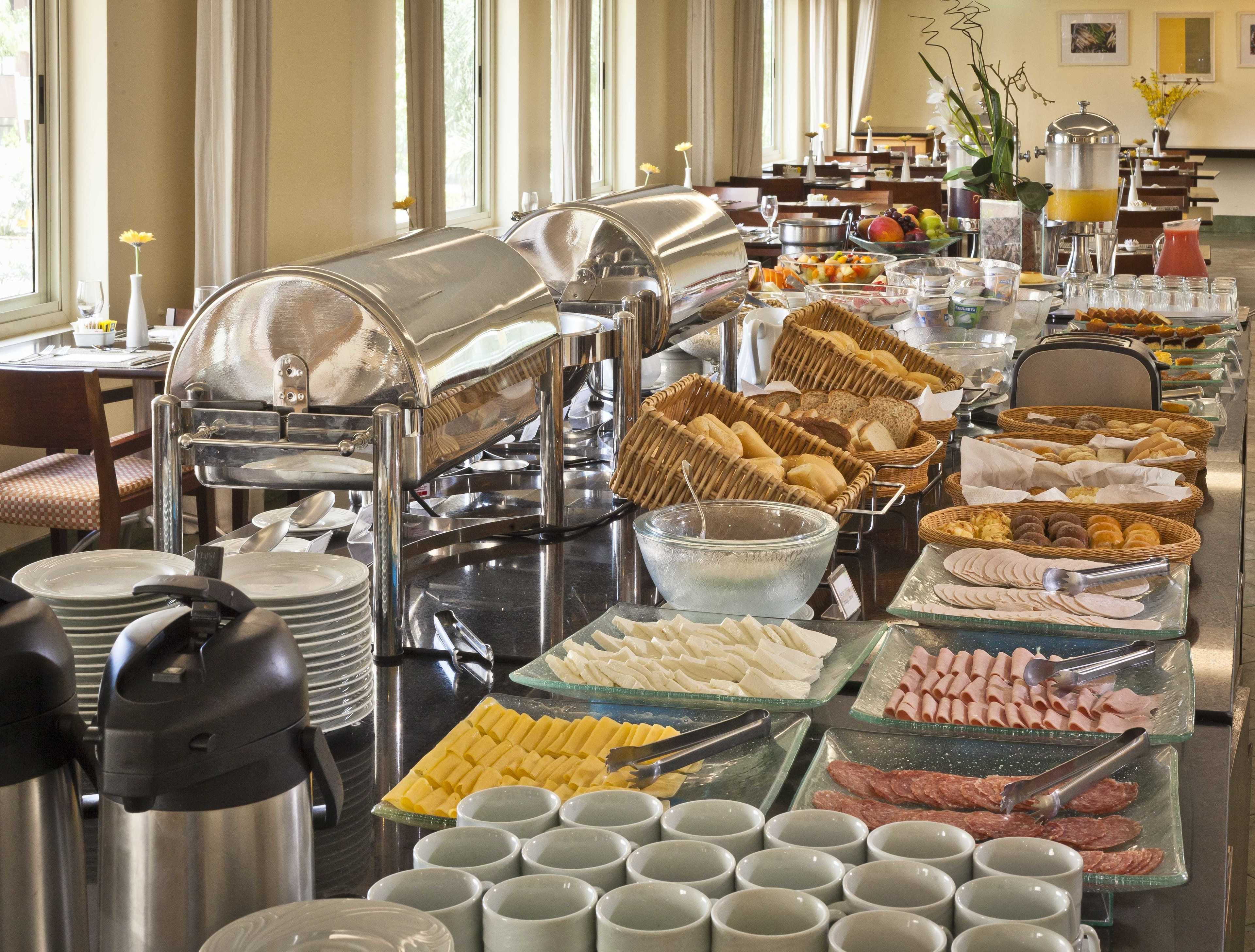 Un bufé con diversos alimentos y bebidas, incluyendo pan, pasteles y bebidas calientes.