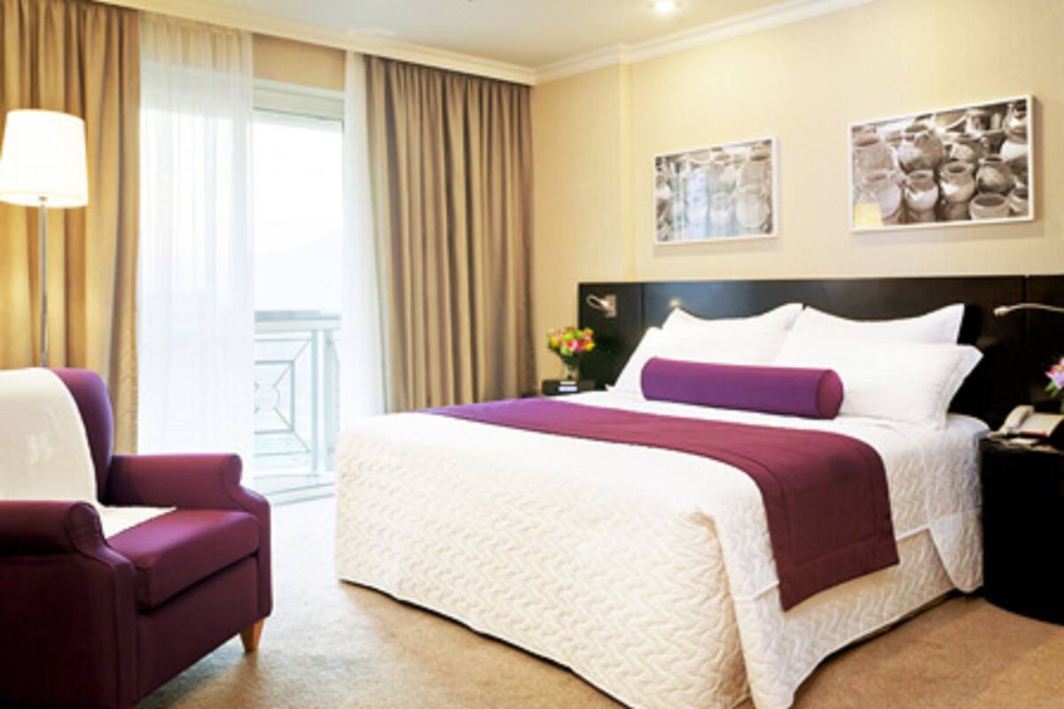 Ein Hotelzimmer mit einem großen Bett, einem Sessel, einem Nachttisch und zwei Bildern an der Wand.