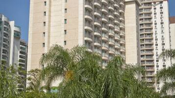 A high-rise hotel with multiple balconies, surrounded by palm trees.