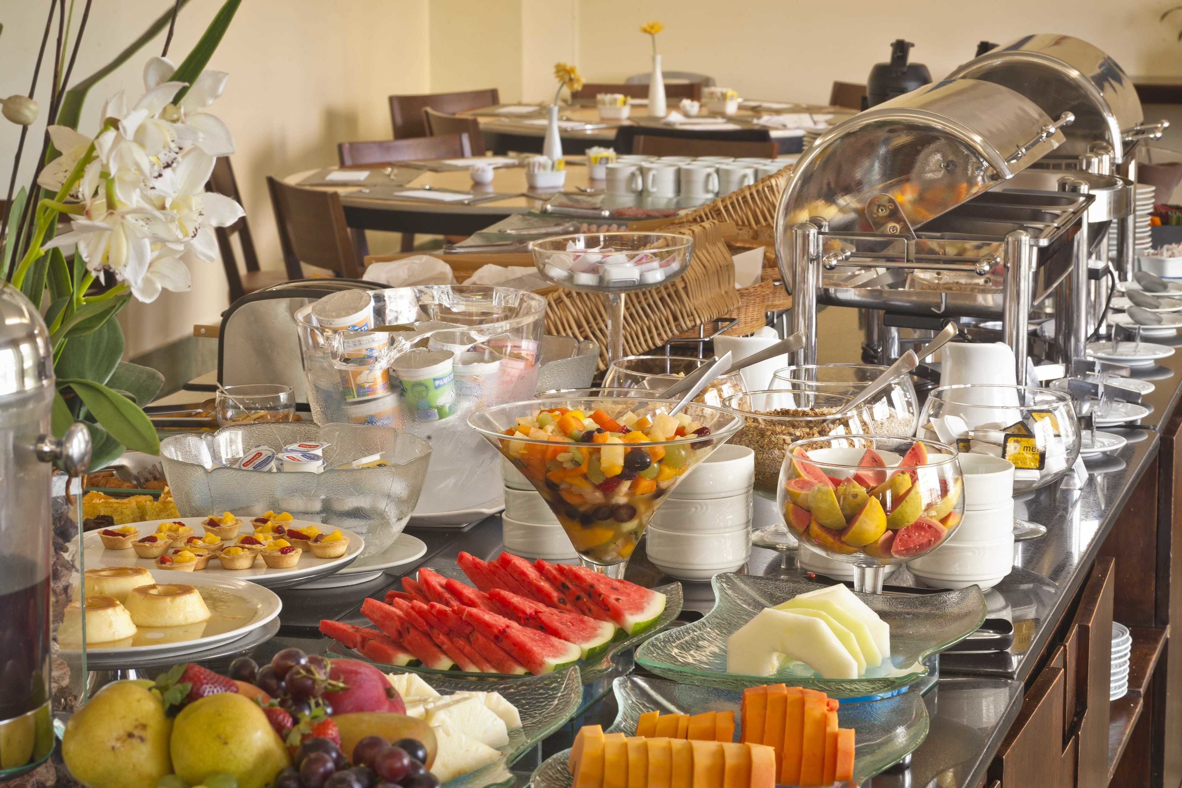 A buffet with various food items including fruits, pastries, and beverages.