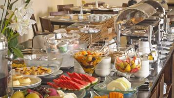 A buffet with various food items including fruits, pastries, and beverages.