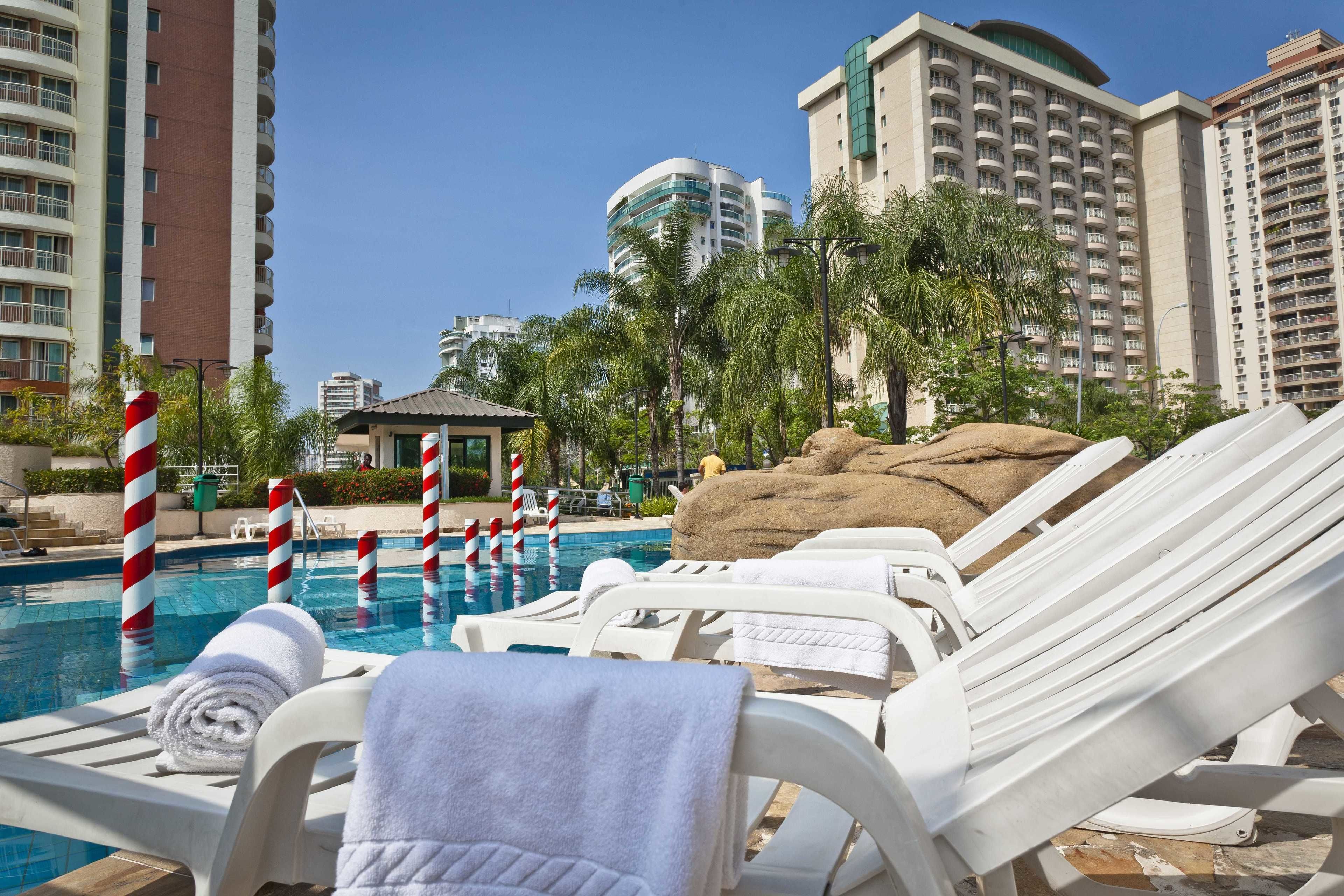 Un espace aménagé au bord de la piscine, avec des chaises longues, un petit kiosque et une formation rocheuse.