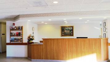 A reception desk with a wooden finish, a clock, and a framed picture on the wall.