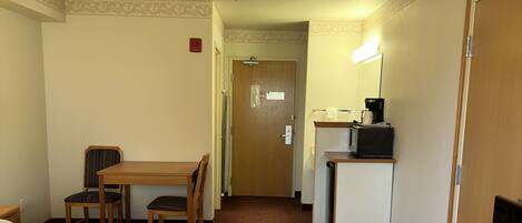 A hotel room with a bed, a desk, a chair, a television, and a microwave.