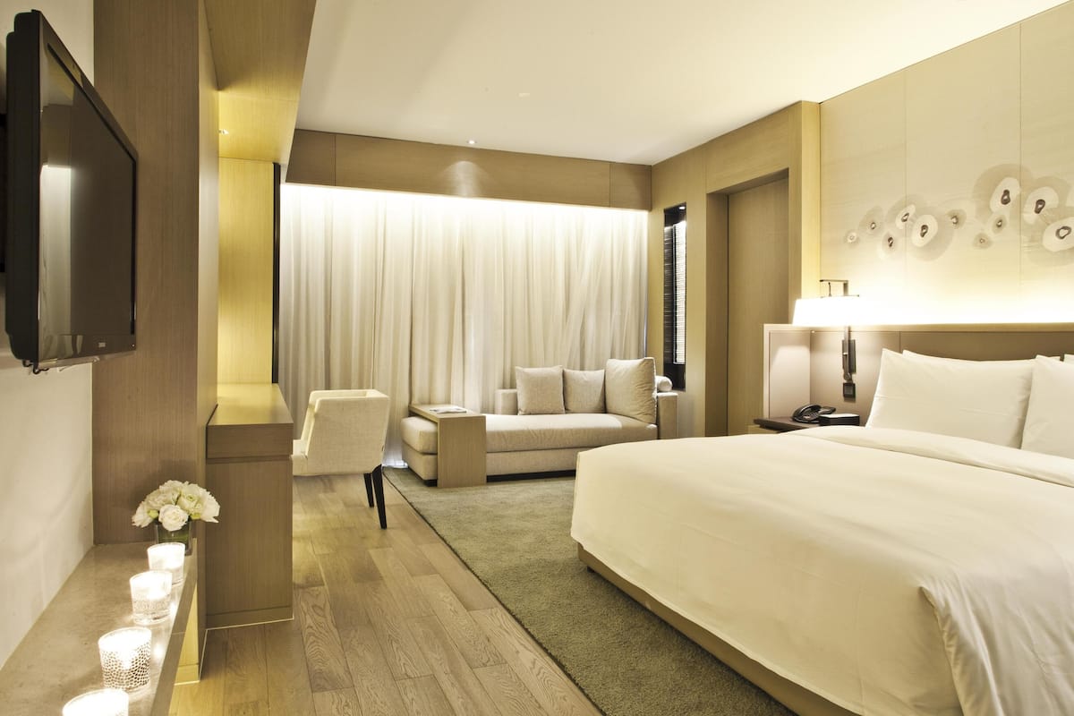 Een moderne hotelkamer met een groot bed, een bank, een bureau en een televisie.