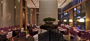 Relax in a stylish space with round tables, cushioned seating areas, and lush greenery.