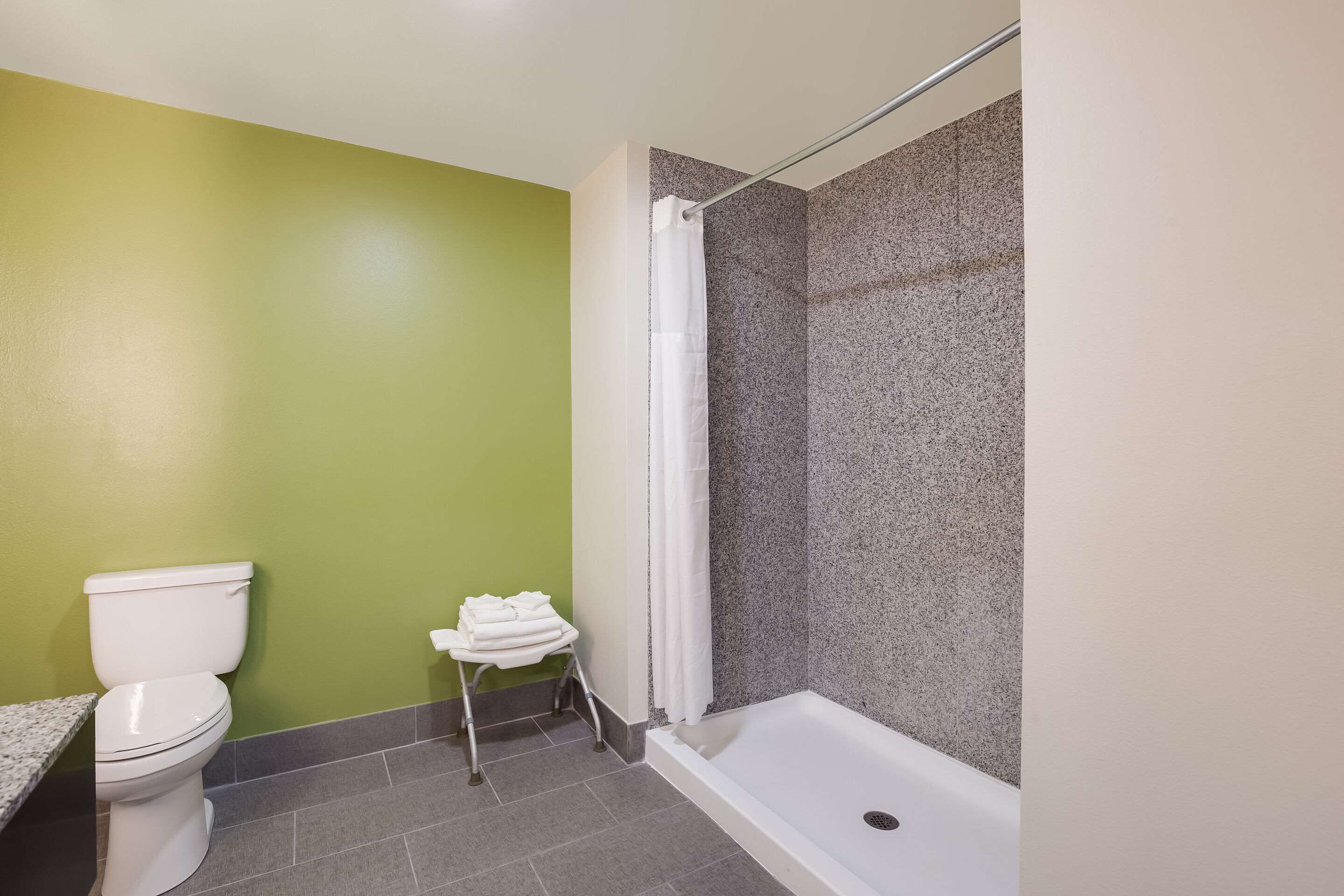 A bathroom with a toilet, a shower with a glass door, and a small towel rack.