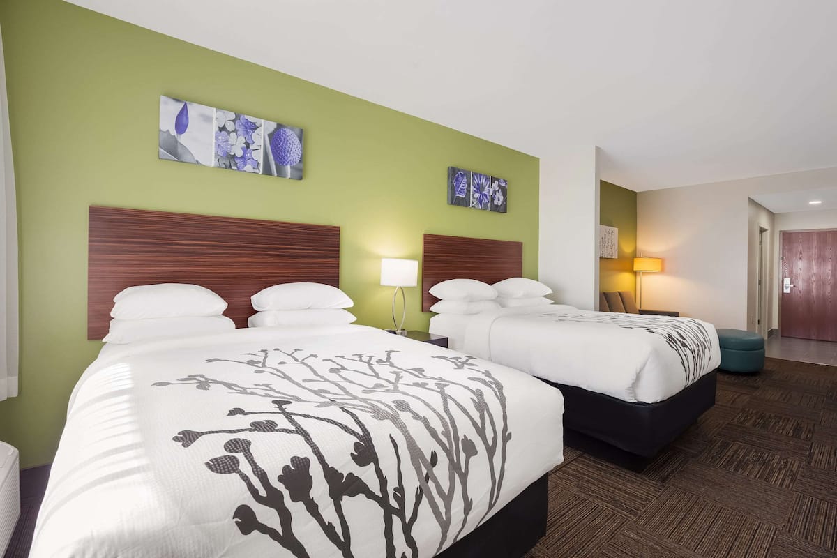 Habitación de hotel con dos camas, paredes verdes y obras de arte en las paredes.