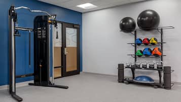 A fitness area with a cable machine, kettlebells, and exercise balls.