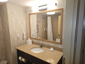 A bathroom with a sink, mirror, towel dispenser, and toilet paper. - Hampton Inn & Suites Prattville (Prattville)