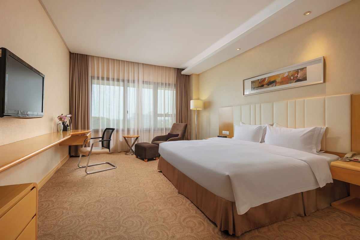 Een hotelkamer met een bed, bureau, stoel en een flatscreen-televisie.