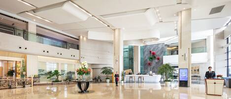 A spacious lobby with a reception desk, seating area, and large windows.