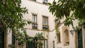 A courtyard with a cobblestone floor, a green door, and potted plants. - B&B Palazzo Bernardini Suite (Lecce)