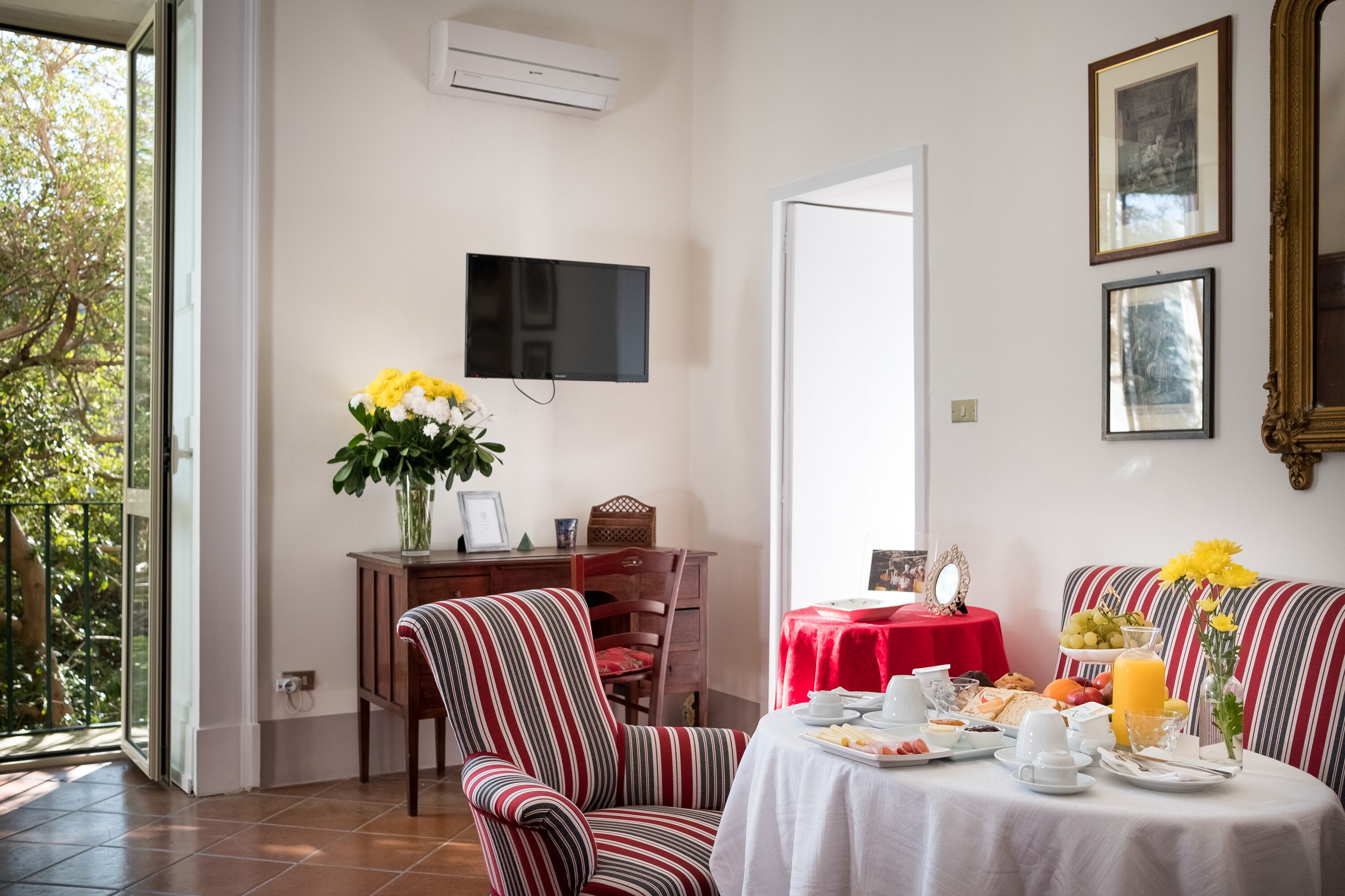 Comedor con una mesa dispuesta para el desayuno, un televisor en la pared y vistas al exterior.