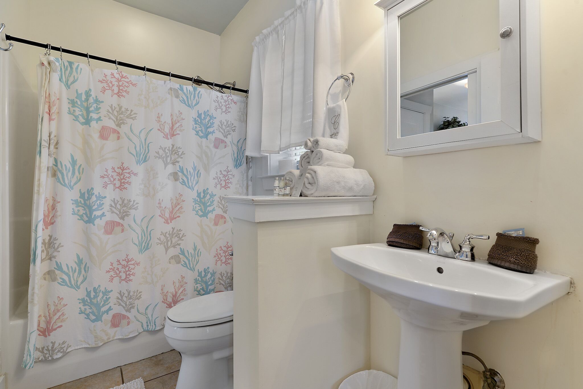 A bathroom with a shower curtain, toilet, sink, and a mirror.