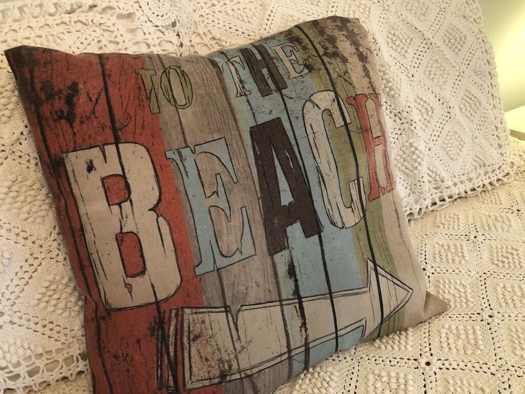 A pillow with the text "TO THE BEACH" on it.