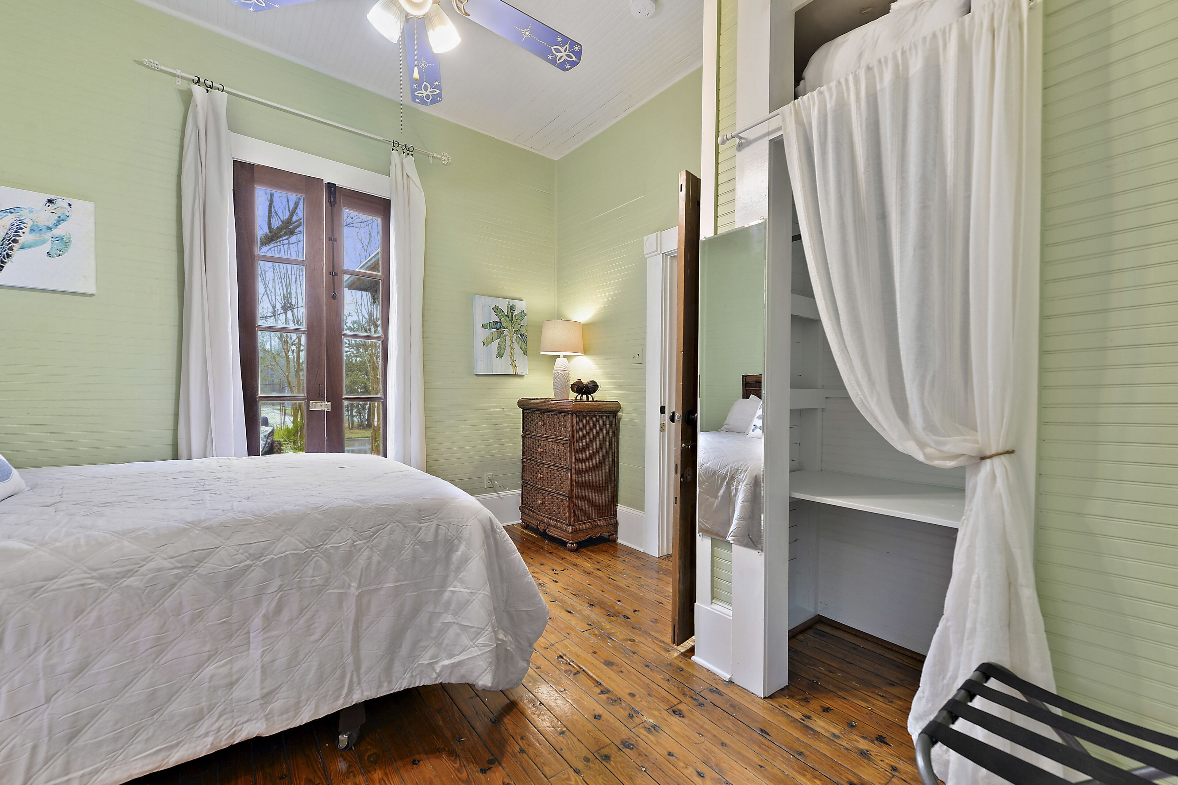 A bedroom with a bed, a dresser, a nightstand, and a window with curtains.