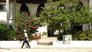 A traditional building with a thatched roof, a white facade, and a sign indicating it is a hotel. - Dhow Inn Boutique Hotel (Paje)