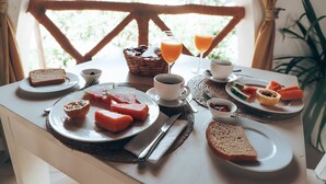 A breakfast table with bread, butter, jam, a cup of coffee, and a glass of orange juice. - Dhow Inn Boutique Hotel (Paje)