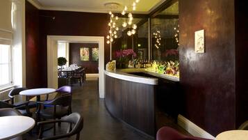 A bar area with a curved counter, multiple seating arrangements, and hanging spherical light fixtures.