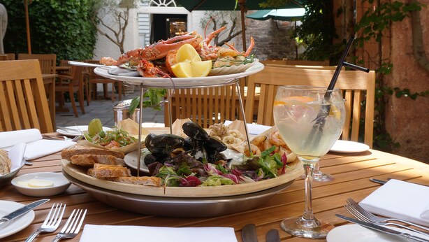 A seafood platter with mussels, shrimp, and bread on a wooden table, accompanied by a glass of white wine and a lemon wedge. - The Angel Hotel Abergavenny (Abergavenny)