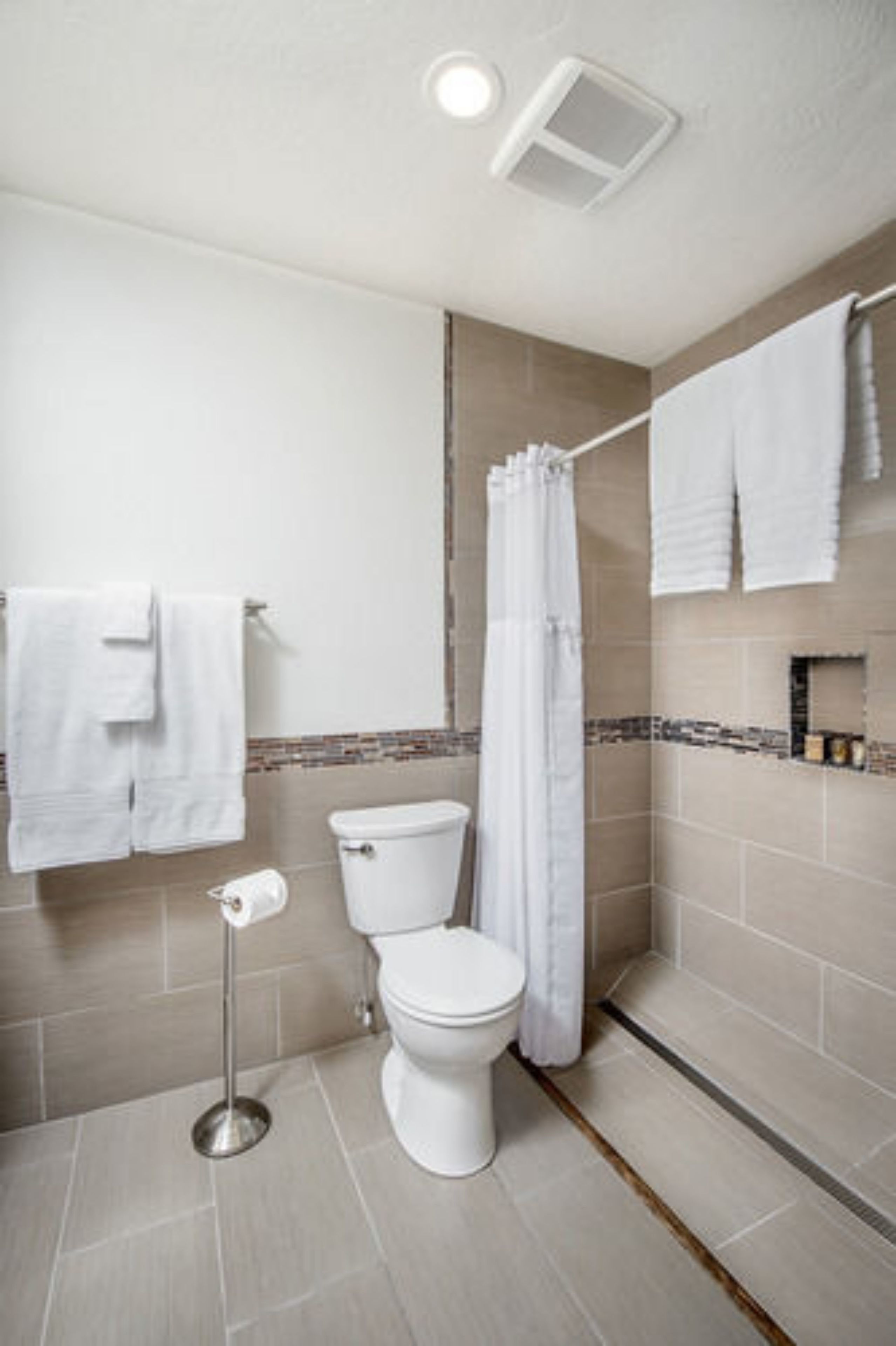 Ein Badezimmer mit Toilette, einer Duschvorhang und einem Handtuchhalter mit mehreren Handtüchern.