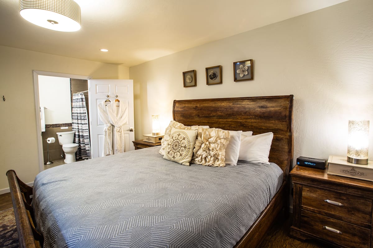A neatly arranged bedroom with a large bed, wooden headboard, and a nightstand with a lamp.