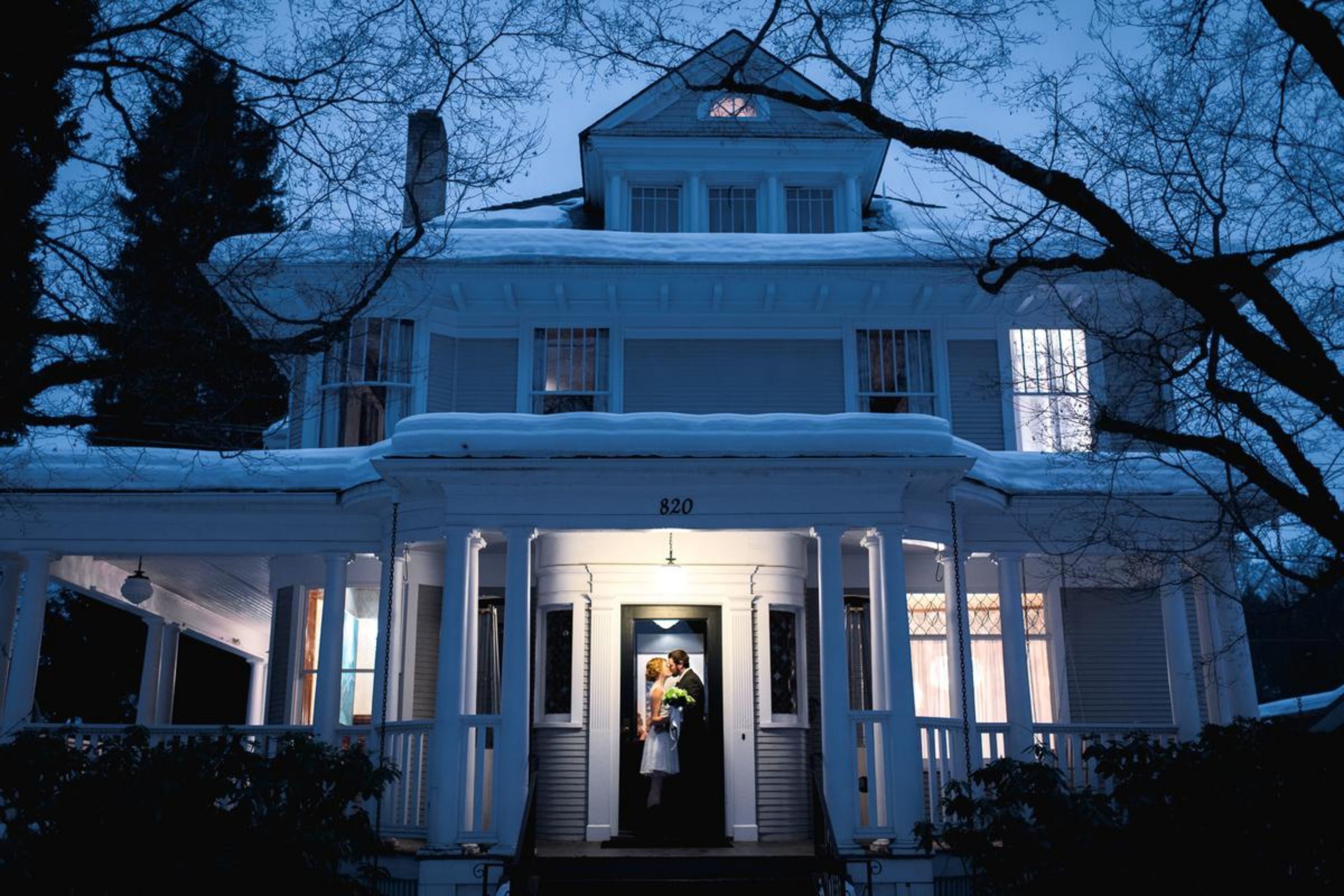 A large white house with a number 820 on the front, a porch, and a staircase leading to the entrance.