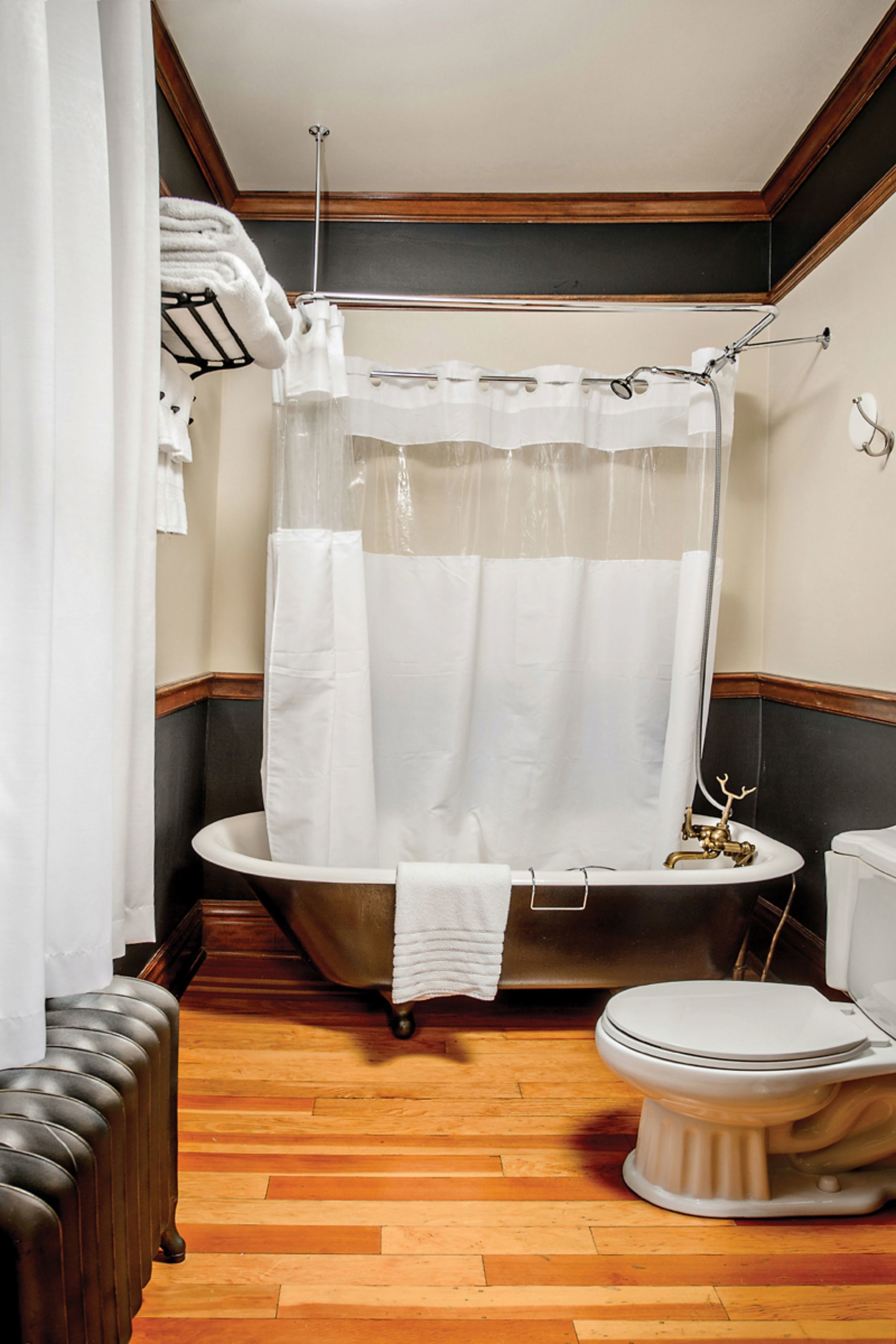 A bathroom with a bathtub, toilet, and wooden floor.