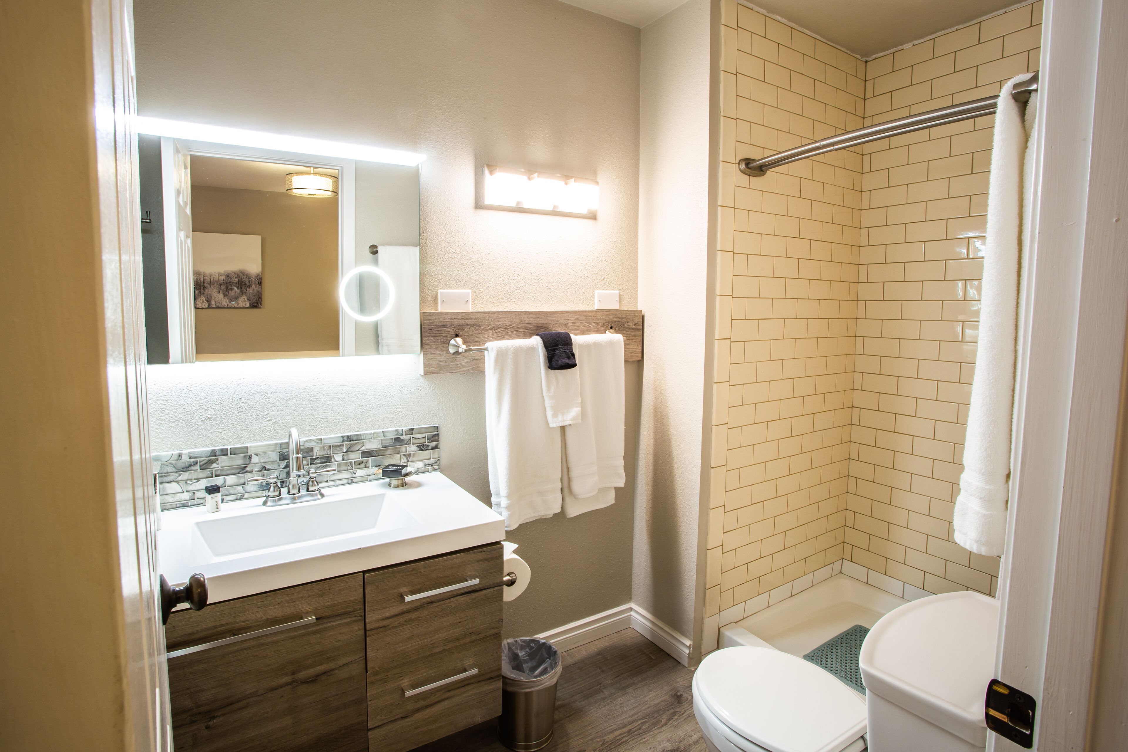 A bathroom with a sink, mirror, towel rack, and a shower area.