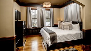 A bedroom with a large bed, a television, and a window with curtains. - Blackwell Hotel (Coeur d'Alene)