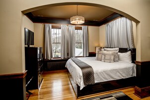 Un dormitorio con una cama grande, televisión y una ventana con cortinas.