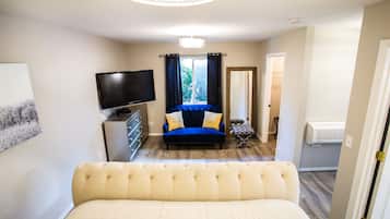 Un dormitorio con cama, televisor, sofá y ventana con cortinas.