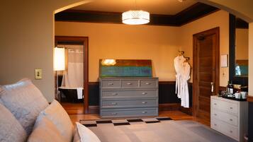 A bedroom with a bed, a dresser, a painting, and a robe hanging on a door.