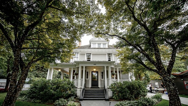A two-story white house with a front porch, surrounded by trees and a well-maintained lawn. - Blackwell Hotel (Coeur d'Alene)