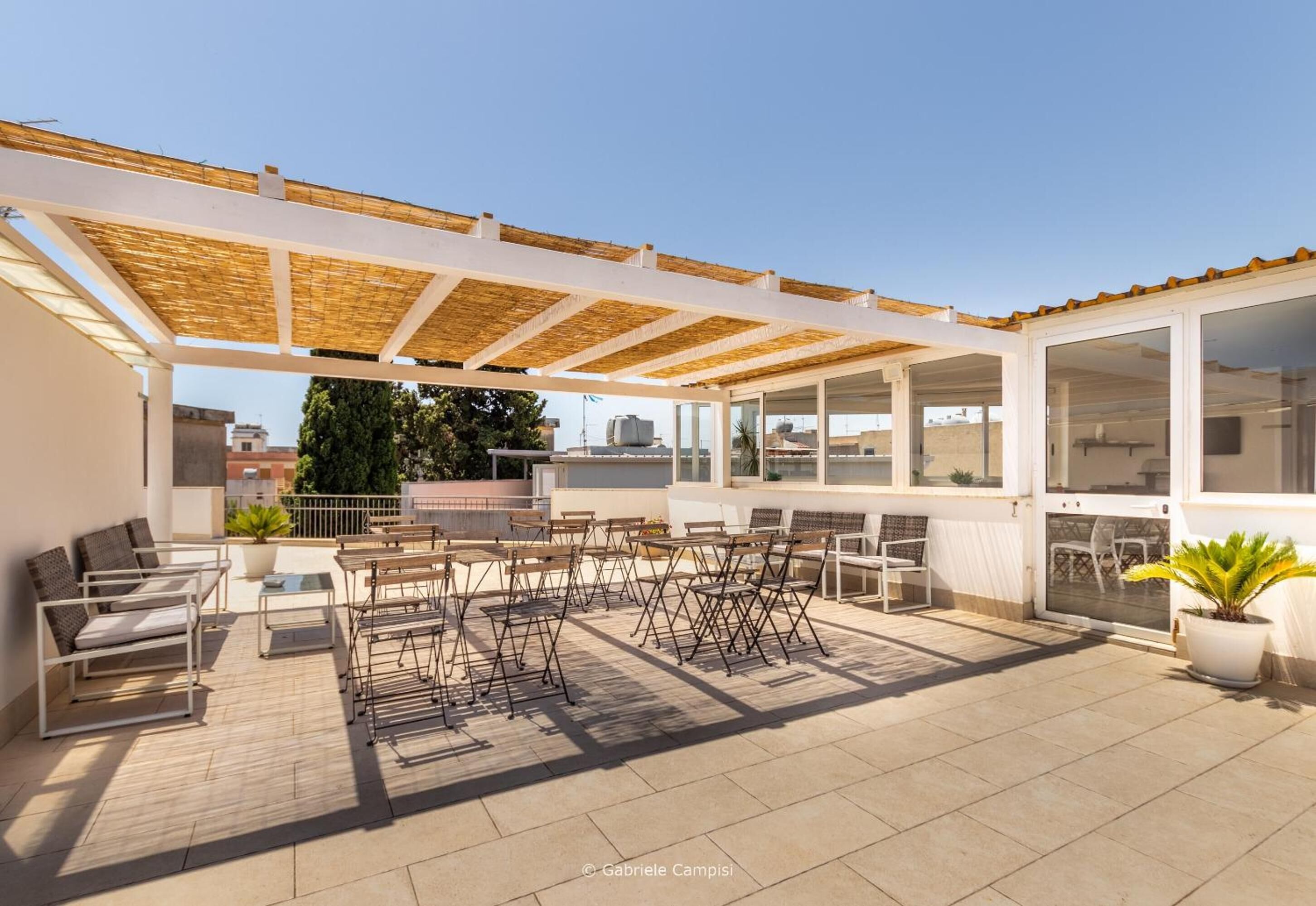 A rooftop terrace with outdoor seating, a pergola, and a view of the city.