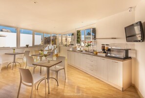 Una cocina moderna con barra para desayunos, armarios blancos y un televisor de pantalla plana.