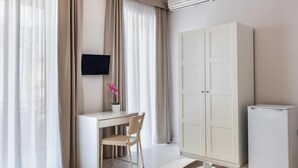 A modern hotel room with a desk, chair, wardrobe, and a flat-screen TV. - Nonna Nina (Avola)
