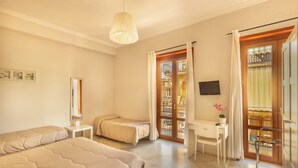 A bedroom with two beds, a desk, a chair, a TV, and a balcony with a view. - Nonna Nina (Avola)