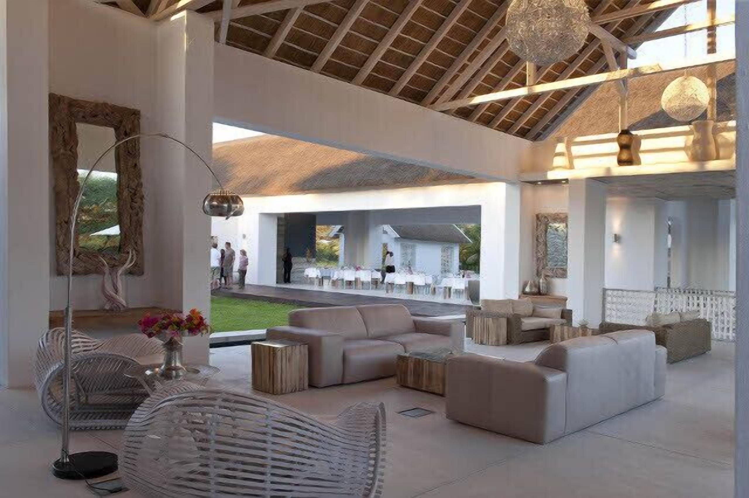 A spacious indoor area with a high ceiling, modern furniture, and a view of an outdoor seating area.