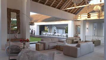 A spacious indoor area with a high ceiling, modern furniture, and a view of an outdoor seating area.