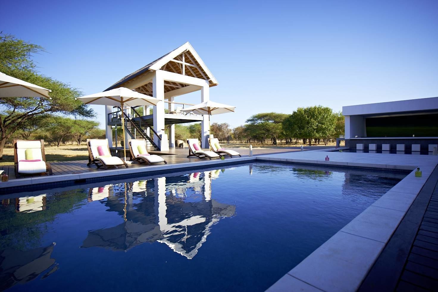 A swimming pool with lounge chairs and a covered structure.