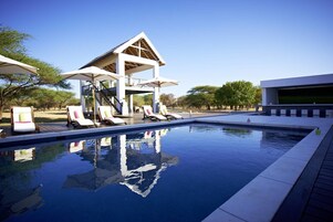 A swimming pool with lounge chairs and a covered structure.
