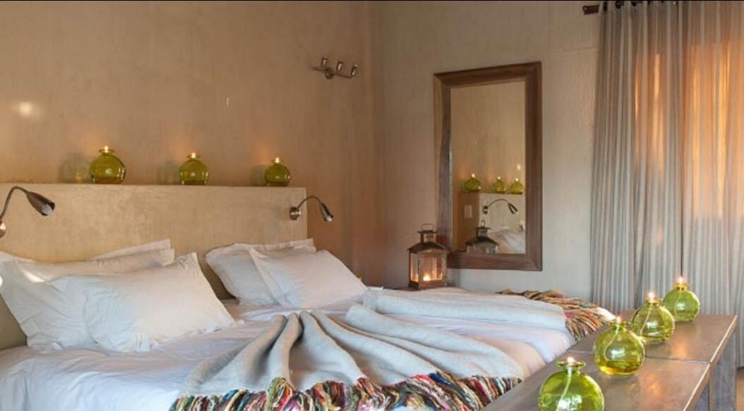 A neatly made bed with white linens, a bedside table with a lamp, and decorative vases.