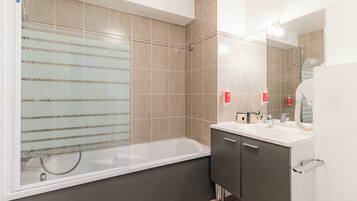 A modern bathroom with a bathtub, a vanity with a mirror, and a shower area.