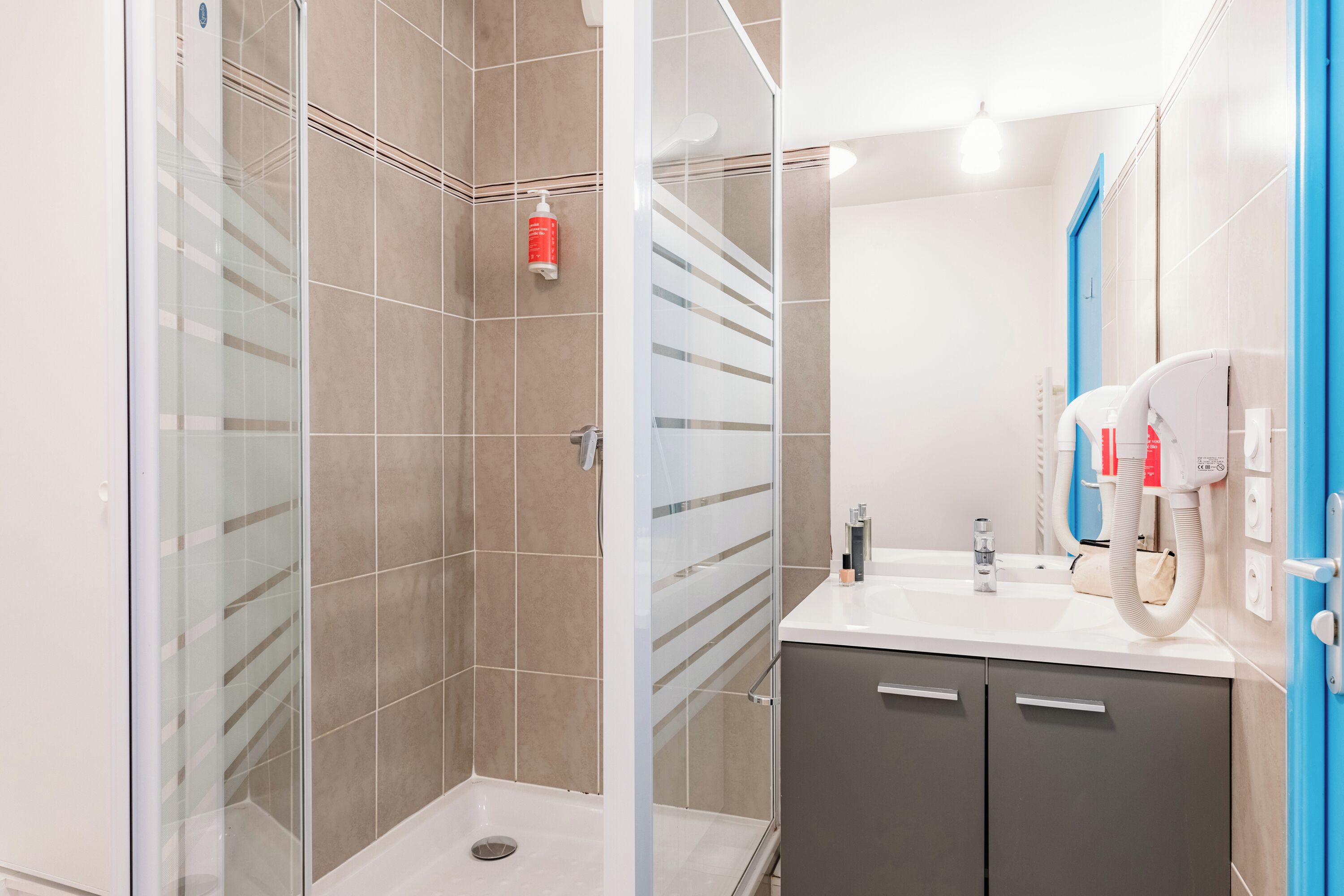 Une salle de bain moderne avec une douche à parois de verre, un lavabo avec un miroir et un distributeur de serviettes.