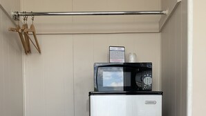 Uma cozinha compacta com geladeira de aço inoxidável e micro-ondas.