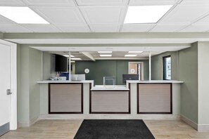 A reception area with a counter, a television, and a door. - Red Carpet Inn- Maple Shade/Philadelphia (Maple Shade)